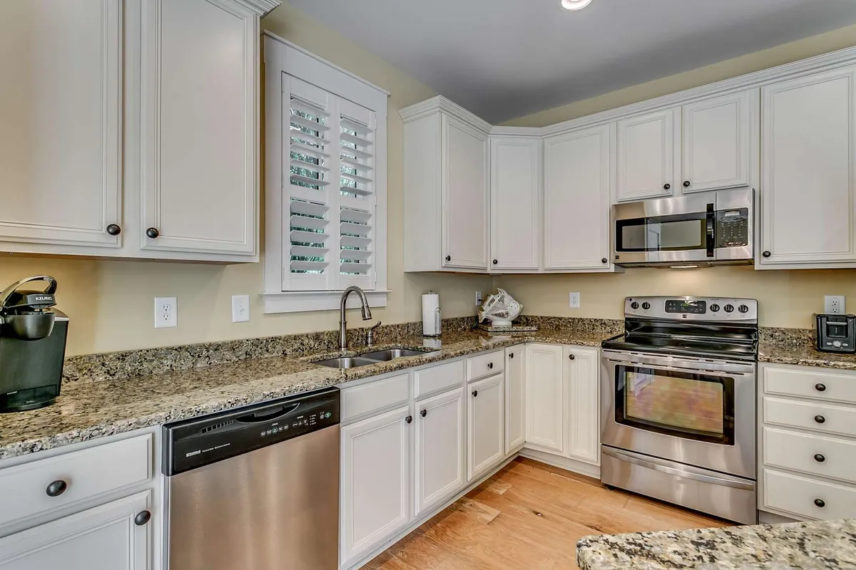 A modern kitchen with granite countertops, stainless steel appliances, and ample cabinetry. The kitchen's open design ensures it is just steps away from living and dining spaces, making snacks and drinks easily accessible.