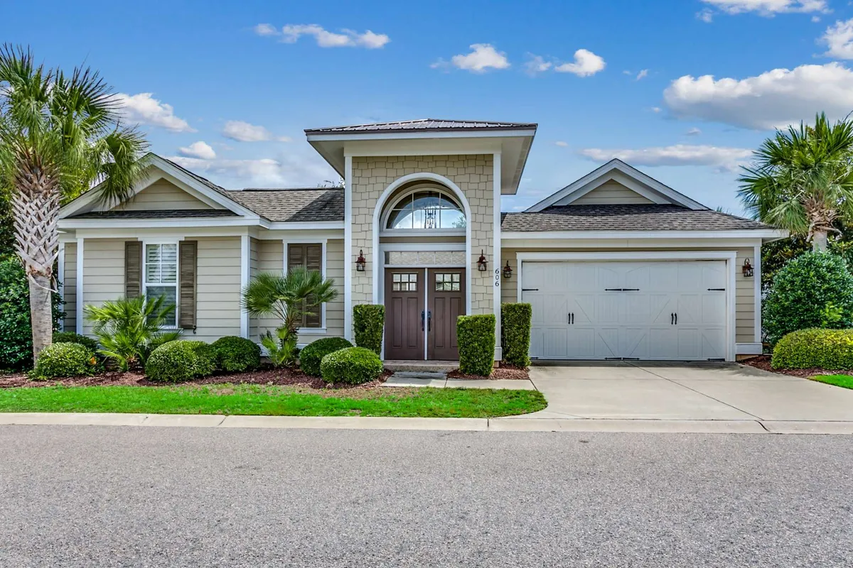 An exterior view of the home’s front door framed by a landscaped garden, with a welcoming porch and a garage. The setting is warm and inviting, hinting at family gatherings, outdoor relaxation, and the convenience of coming and going for beach and poolside adventures.