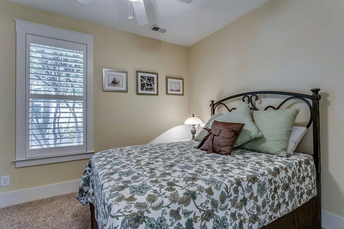 A cozy guest bedroom adorned with floral bedding, decorative pillows, a bedside lamp, and framed artwork. The color palette and soft textures evoke feelings of comfort and warmth, inviting restful sleep and quiet moments.