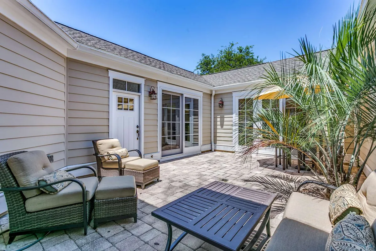 A comfortable and serene outdoor dining area with a dining table surrounded by palm plants, offering a tranquil space for socializing, eating, or relaxing. The mood is peaceful, with soft natural lighting suggesting both daytime and evening use.